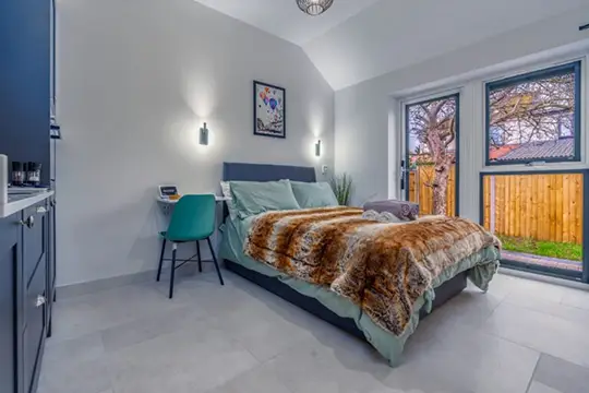 Bedroom with fur throw, blue chair, and bright window