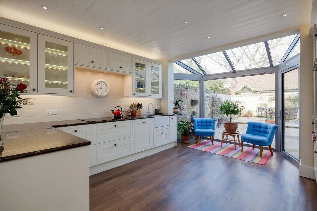 Modern white kitchen with conservatory extension, blue accent chairs and glass roof - professional property management by Upgraded Property Management