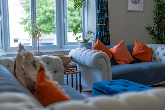 Living room with blue sofa, orange cushions, and sunlight
