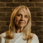 Portrait of woman with blonde hair against brick wall